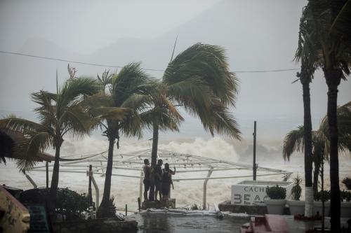 People stand next tp swaying palm trees following the passing of Tropical Storm Lidia in Los Cabos